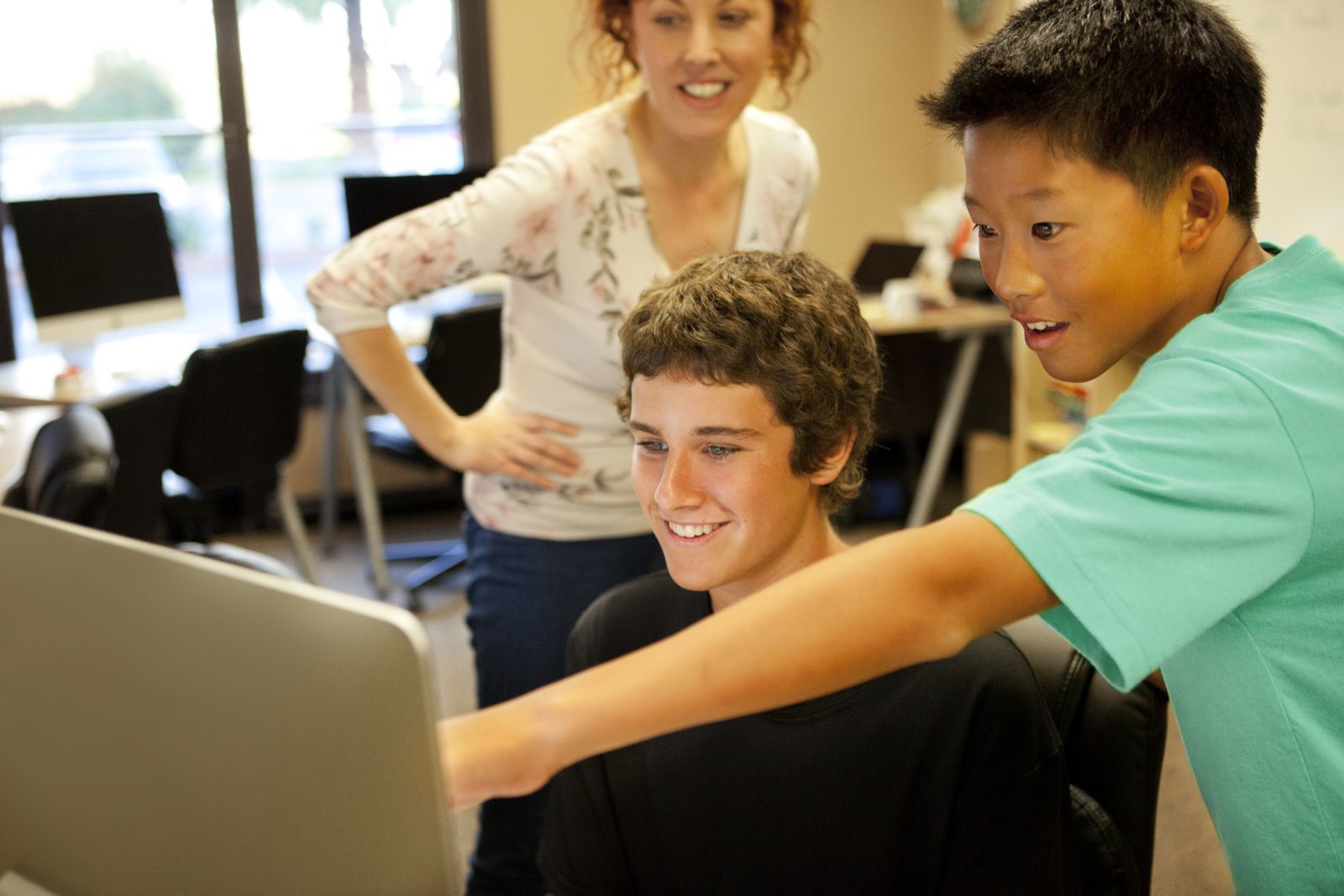 Three students laughing at a laptop