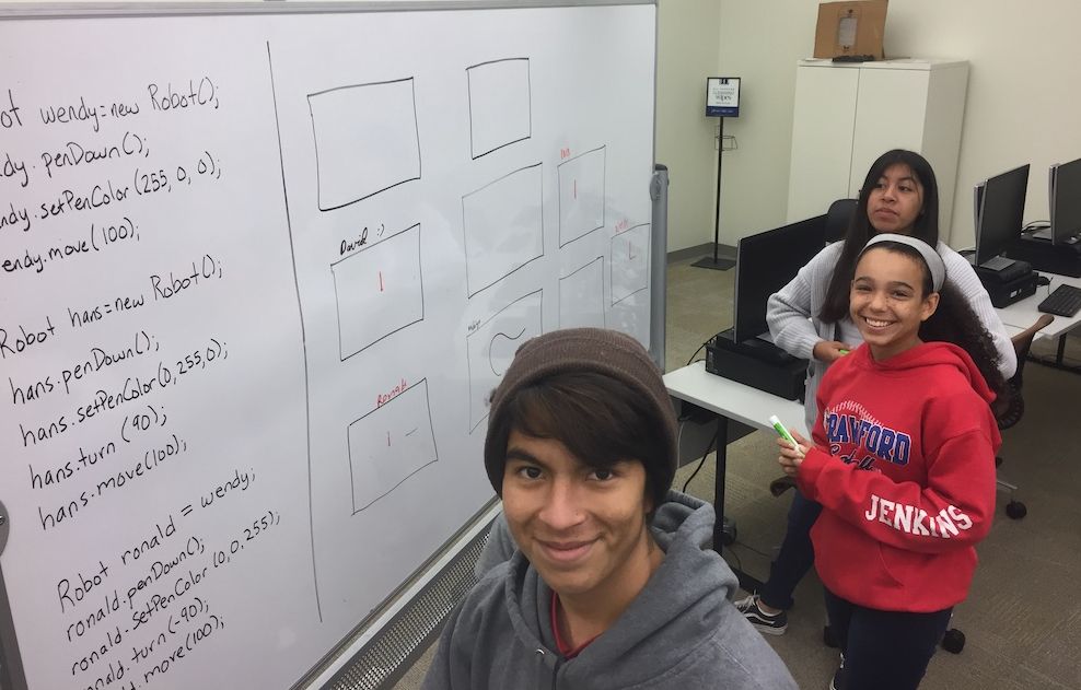 Students working out a problem at a whiteboard